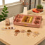 Decorative tray with confectionery and nuts on a table with plants and apples in the background