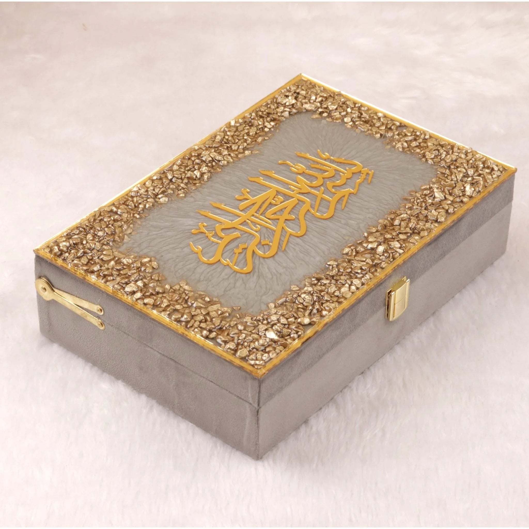 Decorative box with gold embellishments and a central design on a light background