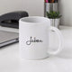 White mug with 'Jabeen' printed on it, placed on a desk with office items in the background.