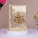 Decorative item with gold sequin cover and Arabic calligraphy on a white surface.