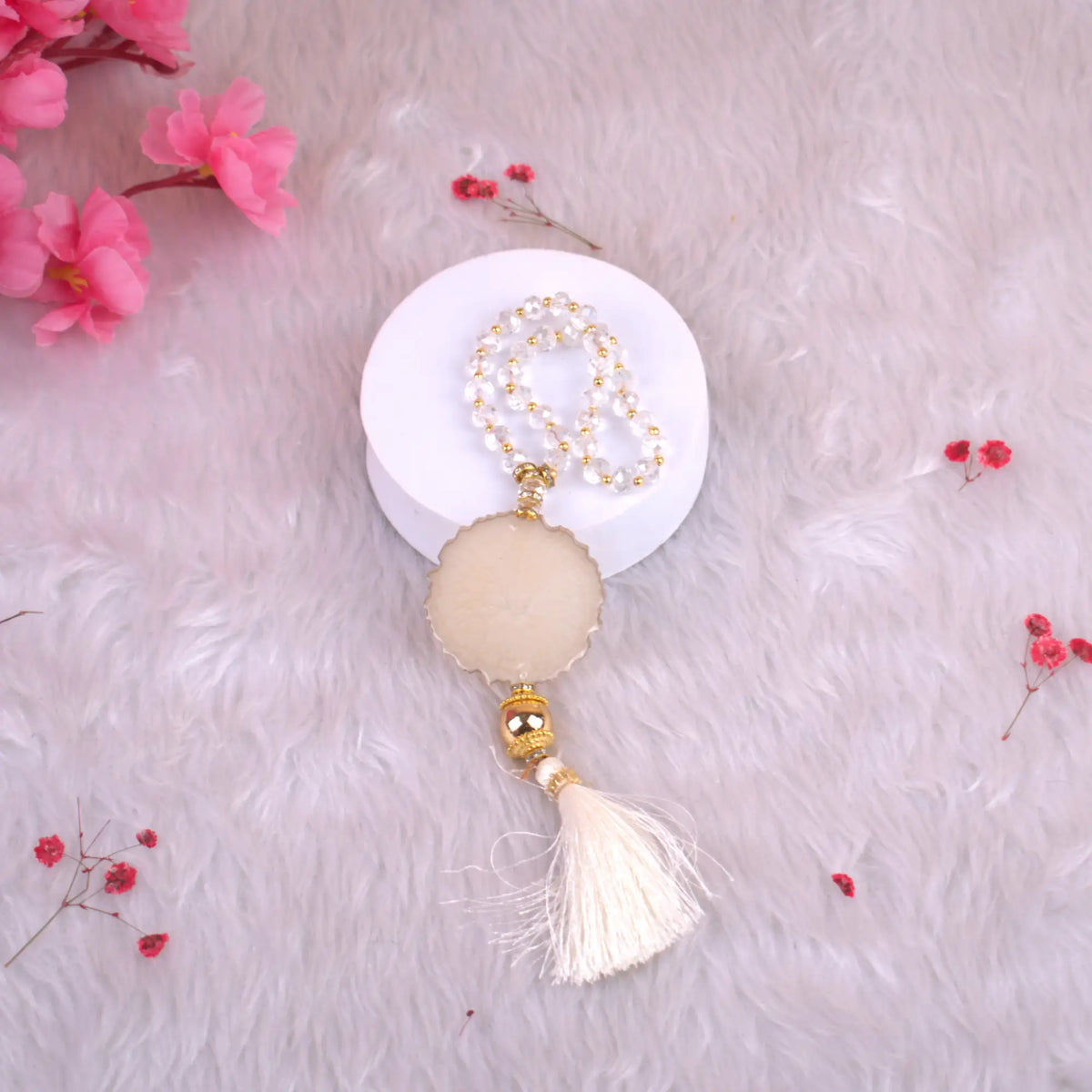 Decorative keychain with tassel on a white surface with pink flowers