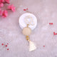 Decorative keychain with tassel on a white surface with pink flowers