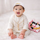 Baby boy with traditional white thobe and red checkered headscarf smiling