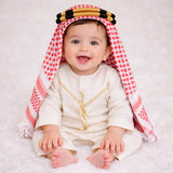Baby boy wearing traditional white thobe with red checkered headscarf