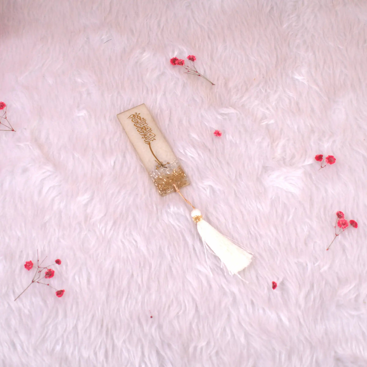 Decorative bookmark with tassel on a soft pink background
