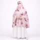 Woman modeling a light pink floral printed prayer makhana (prayer dress) with an attached face veil, paired with a white skirt against a white background.
