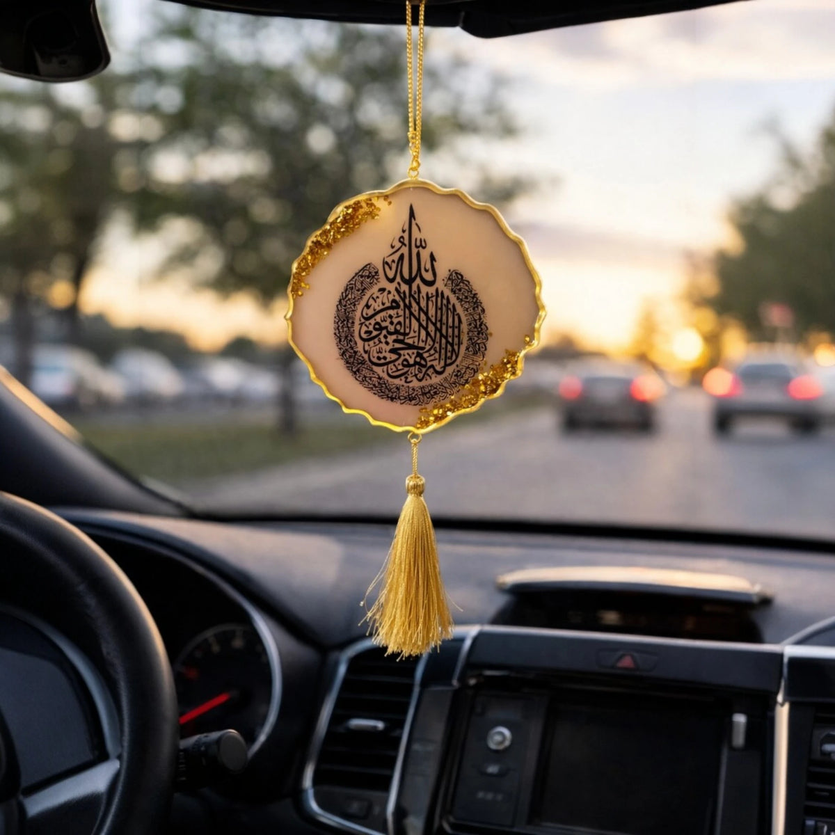 Decorative hanging car ornament with tassel inside a car, blurred street view outside.
