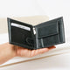 Hand holding black leather wallet with yellow stitching and card slots