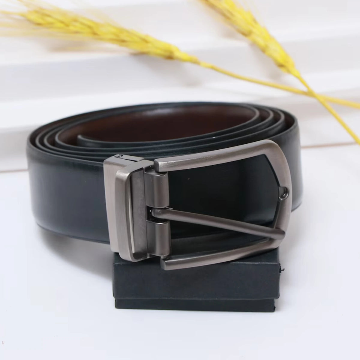 Metal belt buckle with leather belt coiled in box