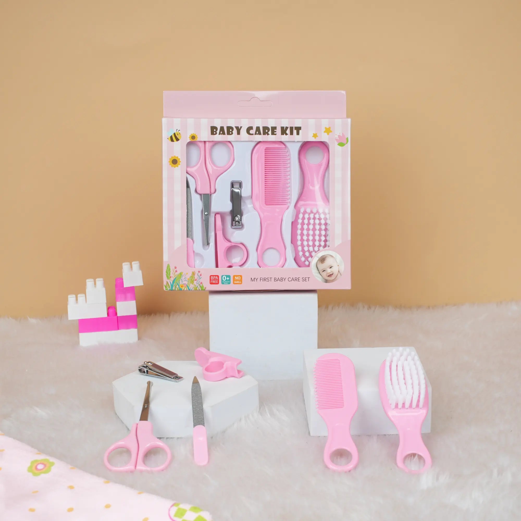 Baby care kit with pink tools and packaging on a beige background
