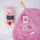A soft pink Women's Namaz Essentials Hamper flat lay, featuring a rolled pink floral prayer dress, a pink velvet prayer mat, a pink mini velvet Quran box, white and pink tasbeeh beads, and a digital counter.