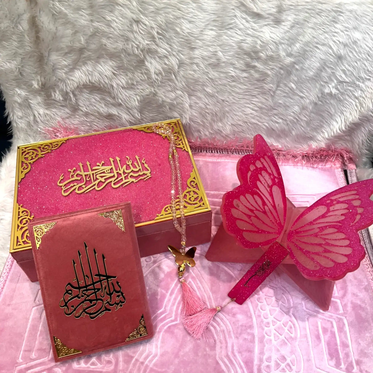 Pink and gold decorative items with Arabic text on a textured white surface