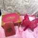 Pink and gold decorative items with Arabic text on a textured white surface