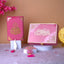 Pink decorative items with Arabic calligraphy on a soft pink surface with flowers and a lamp.