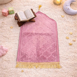 Pink Kids Dome Janamaz with gold fringe, displayed in a cozy prayer setup with Quran, moon pillow, and toys, ideal for children aged 3 to 10.