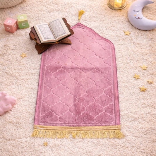 Pink Kids Dome Janamaz with gold fringe, displayed in a cozy prayer setup with Quran, moon pillow, and toys, ideal for children aged 3 to 10.