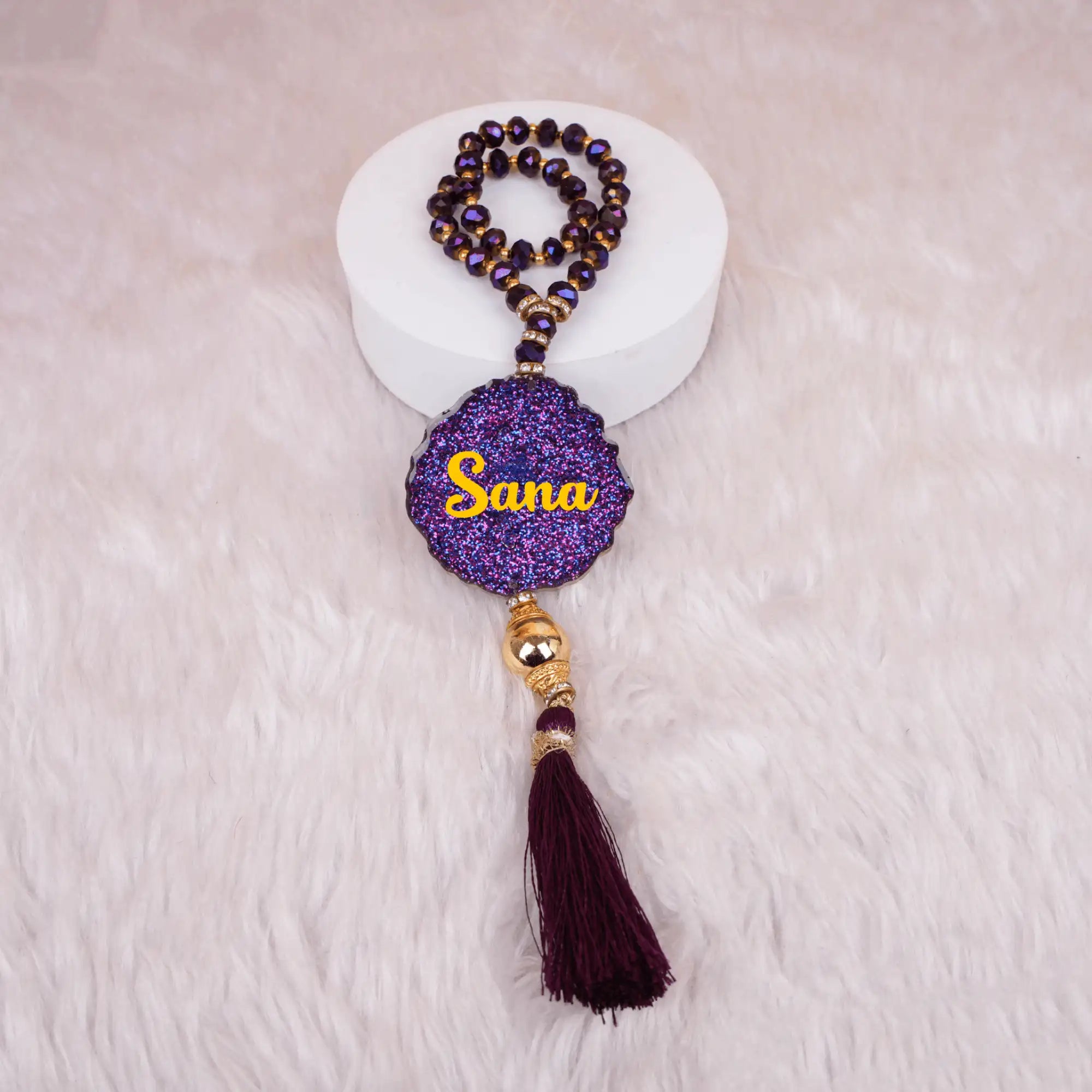 Kids Glitter Tasbeeh with 33 crystal beads in deep purple, featuring a personalized 'Sana' name tag and maroon tassel, ideal for Islamic gifts. Main image