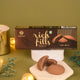 Close-up of Kanha brand Rich Fills chocolate cookies, showing the box packaging alongside loose cookies broken open to reveal their gooey chocolate centers, set against a soft green background with warm fairy lights.