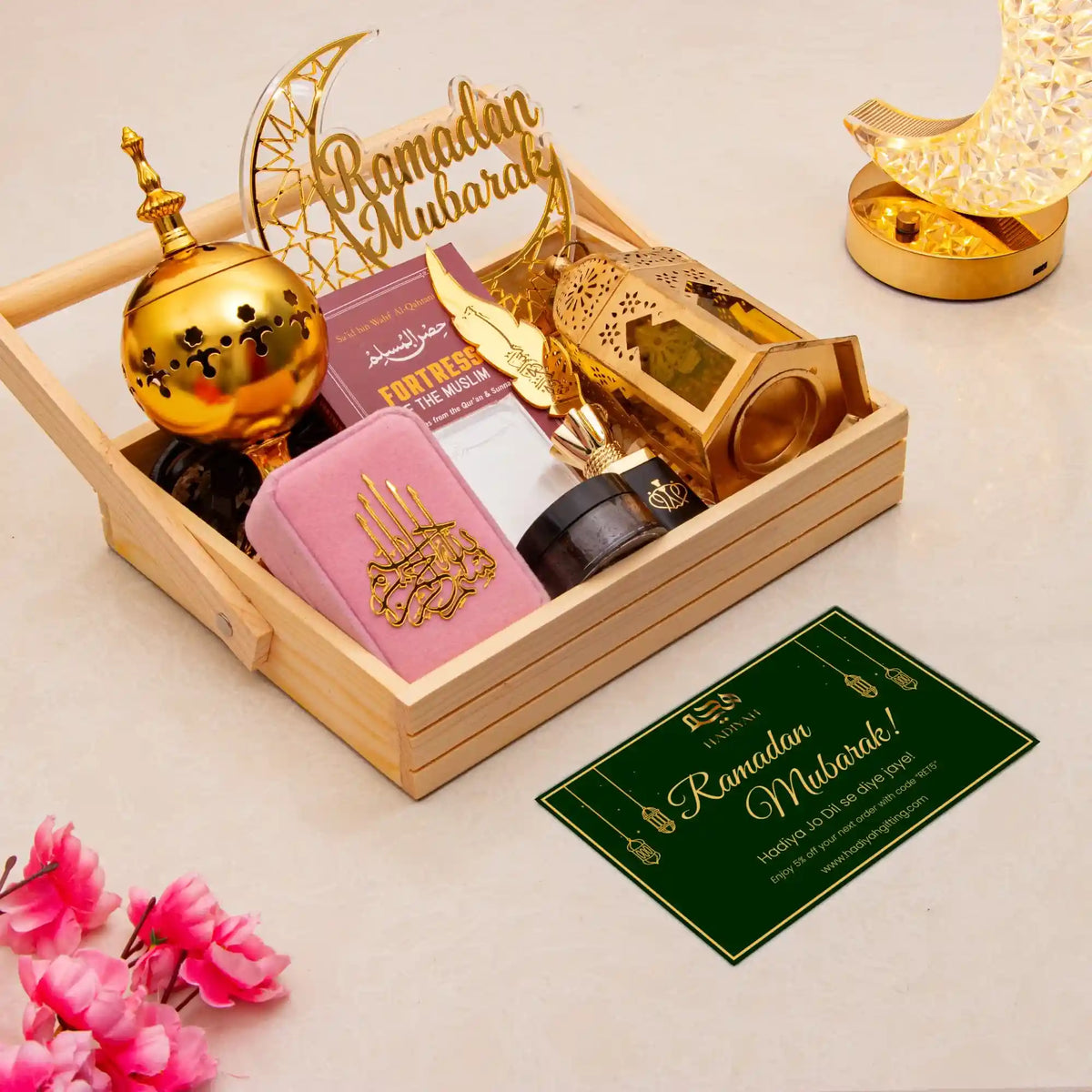 Decorative set with gold lanterns, pink box, and 'Ramadan Mubarak' sign on a light background.