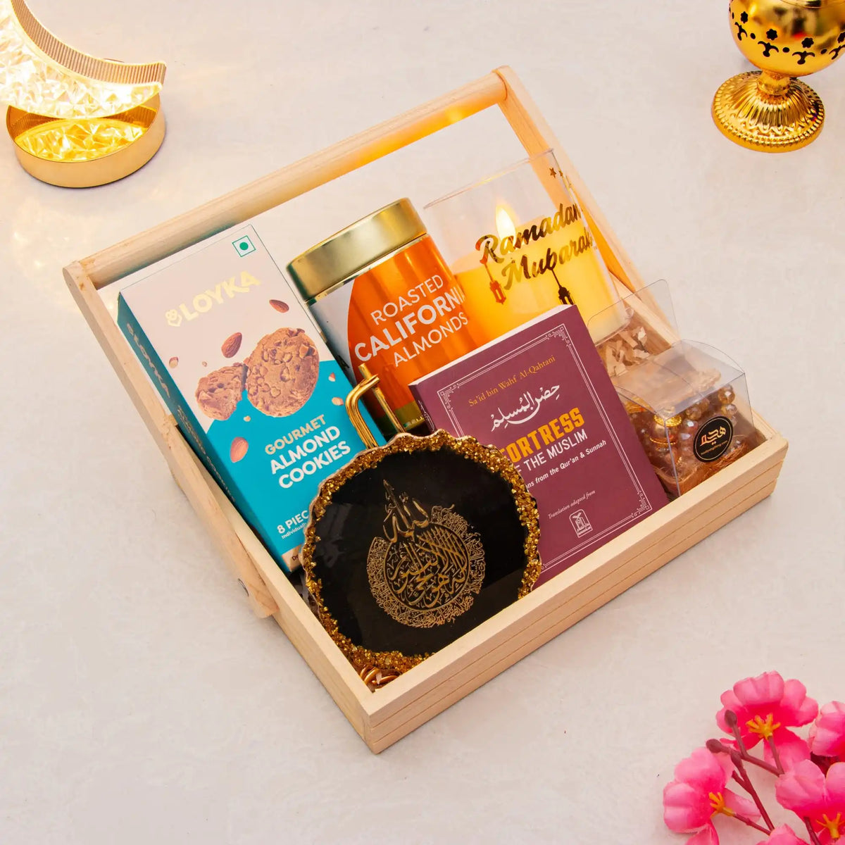 Gift basket with cookies, almonds, and a necklace on a light surface.