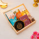 Gift basket with cookies, almonds, and a necklace on a light surface.