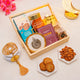 Gift basket with cookies, almonds, and a rosary on a light surface with flowers and lanterns.