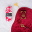 Red Sajdah Serenity Hamper displayed on a white fluffy surface, including a red velvet janamaz, a mini red velvet Quran, a red crystal tasbeeh, and a rolled-up red and white floral prayer makhana.