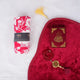 Red Sajdah Serenity Hamper displayed on a white fluffy surface, including a red velvet janamaz, a mini red velvet Quran, a red crystal tasbeeh, and a rolled-up red and white floral prayer makhana.