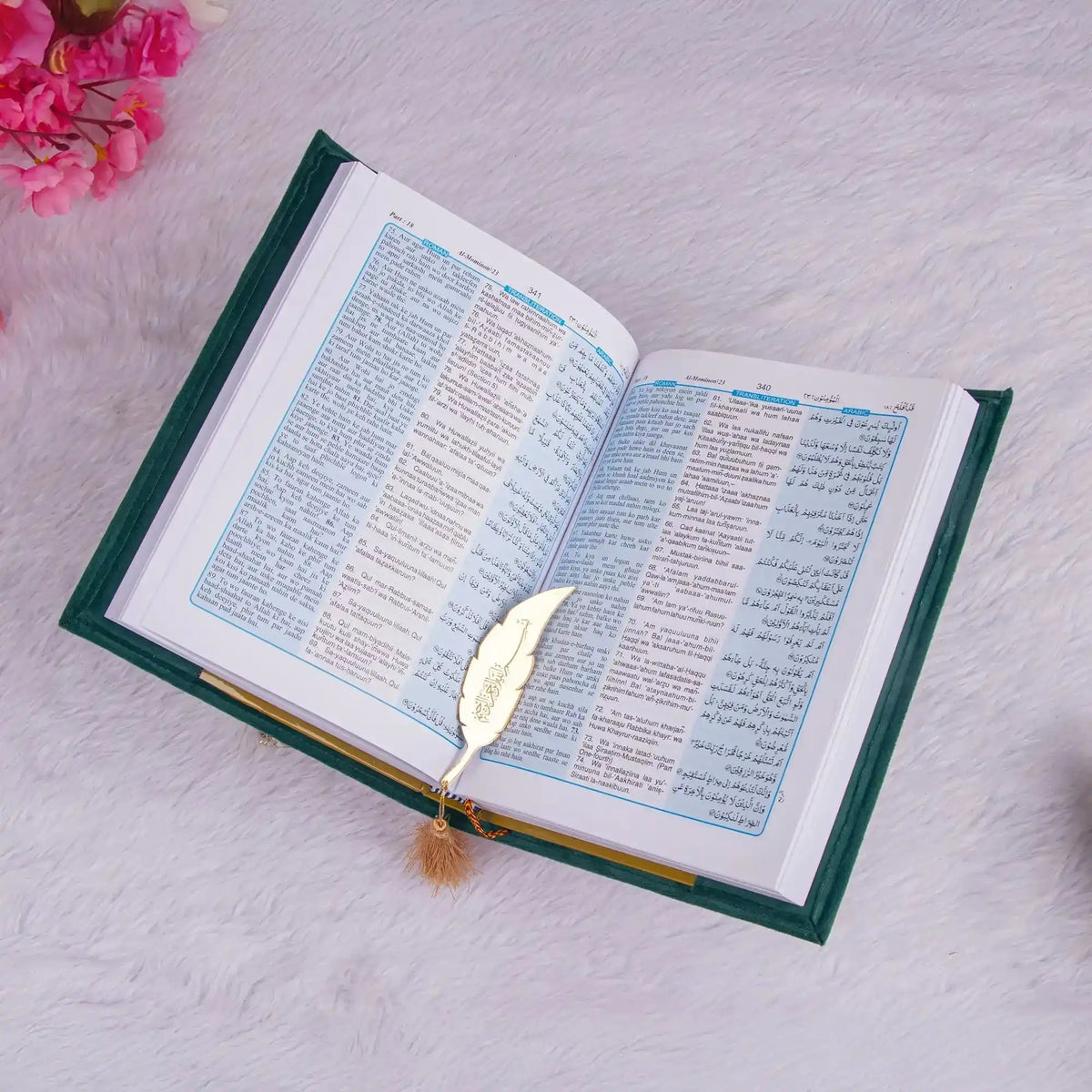 Open book with a decorative leaf bookmark on a light pink surface with pink flowers.