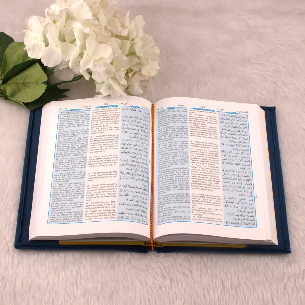 Open book with text on a light surface next to white flowers