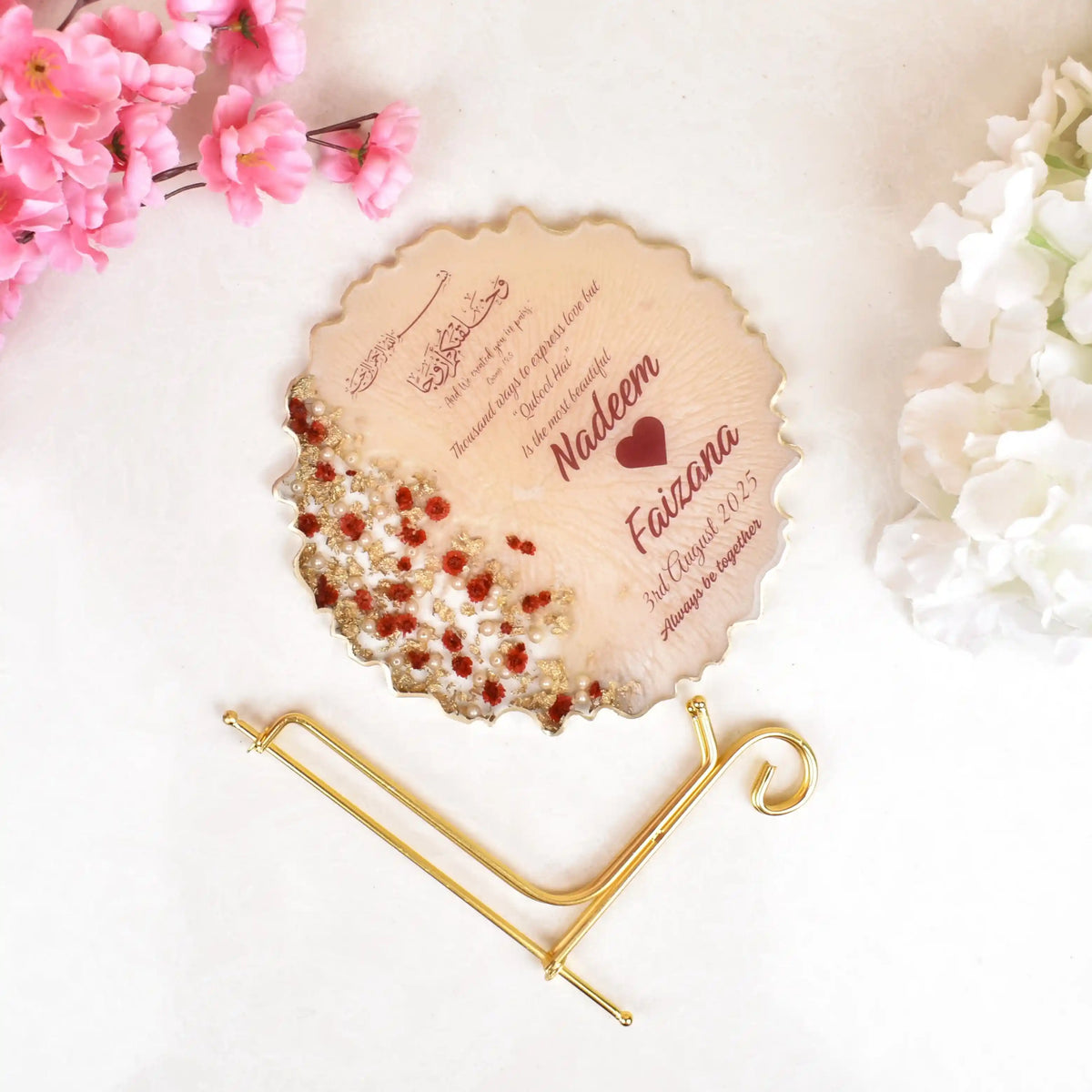 Personalized round plaque with engraved text on a decorative stand with flowers in the background