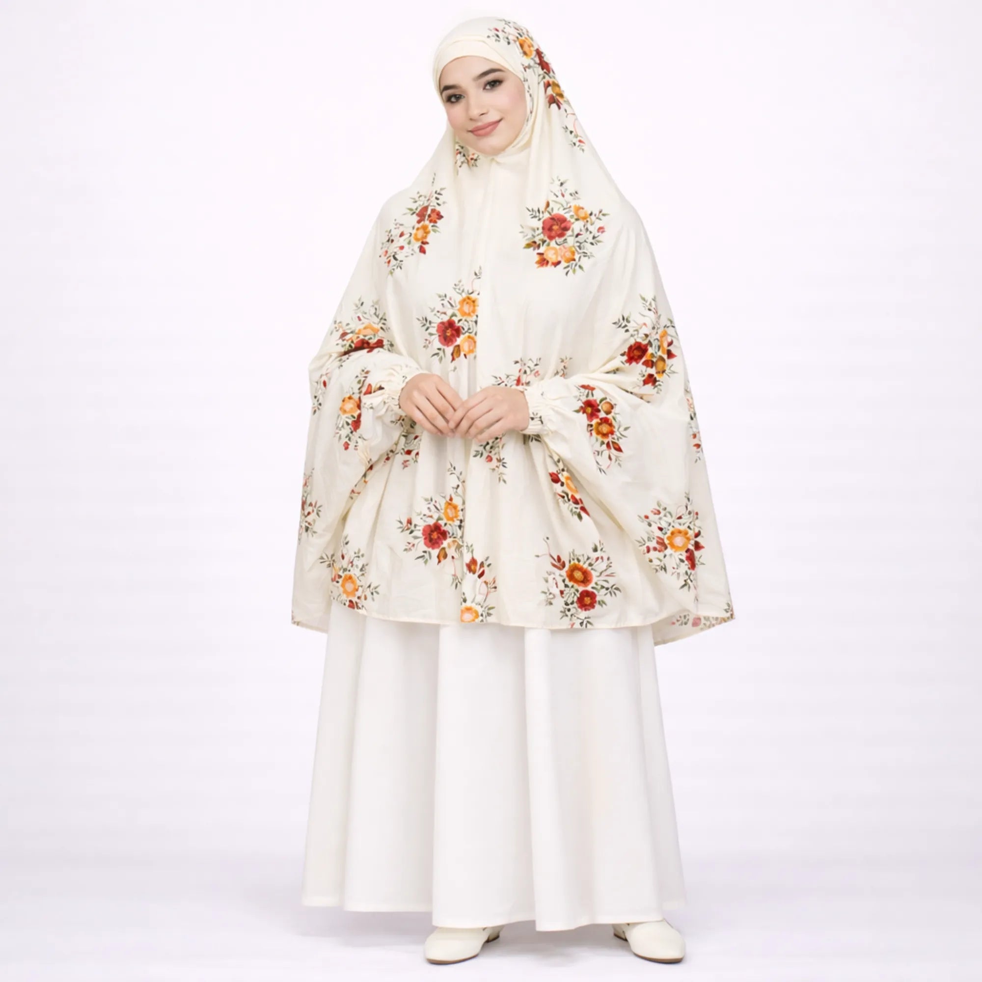 A smiling woman wearing an off-white, half-length prayer dress featuring red and orange floral patterns over a solid white skirt. Main image