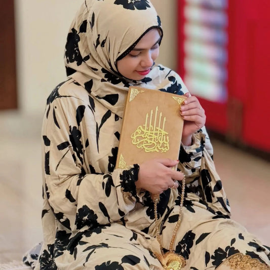 Woman in floral hijab holding a tan Quran from the Personalized Salah Gift Set - Prayer Essential Quran Gift Sets, ideal for Ramadan gifting.
