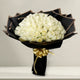 Elegant Peaceful White Roses Bouquet featuring 100 white rose stems wrapped in black paper with gold ribbon, perfect for sympathy or special occasions.