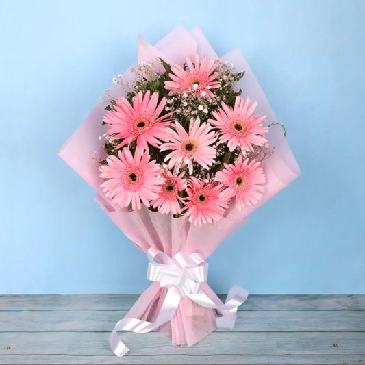 Magic Love - Pink Floral Bouquet featuring fresh pink gerbera daisies wrapped in pastel paper with white ribbon. Ideal for expressing affection on special occasions.