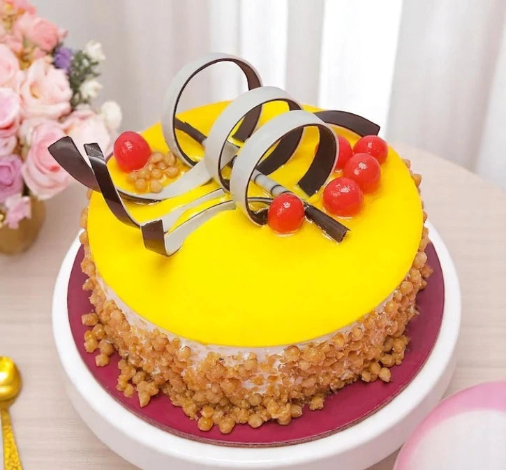 Butterscotch Cake Caramel Drizzle topped with chocolate curls and cherries, decorated with roasted nuts on the sides, ideal for same day delivery. Main image