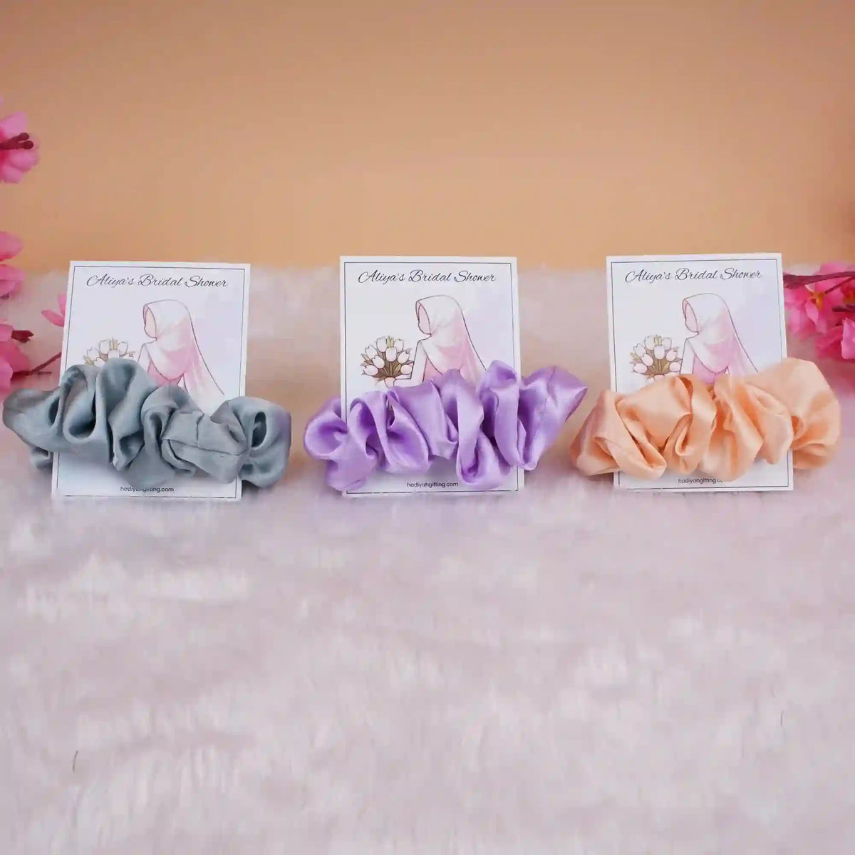 Set of three satin scrunchie bridal shower favors in grey, lavender, and peach with personalized cards, perfect for wedding gifts.