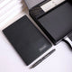Black textured desk mat with a silver pen on white marble surface