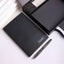 Black textured desk mat with a silver pen on white marble surface