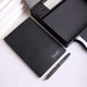 Black textured desk mat with a silver pen on white marble surface
