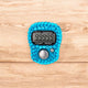 Close-up of turquoise digital tasbeeh counter with 99999 count. Modern zikr tool for spiritual connection.