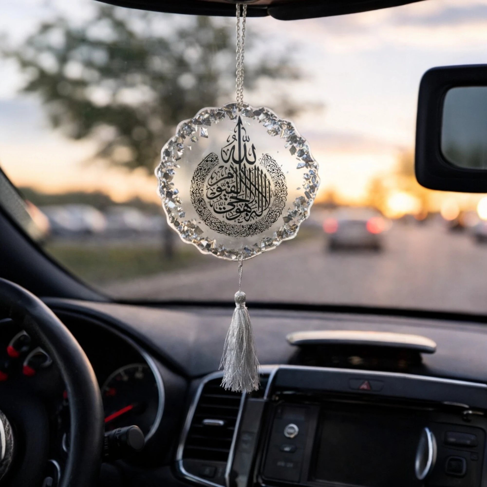 Decorative car hanging with tassel inside a car during sunset. Main image