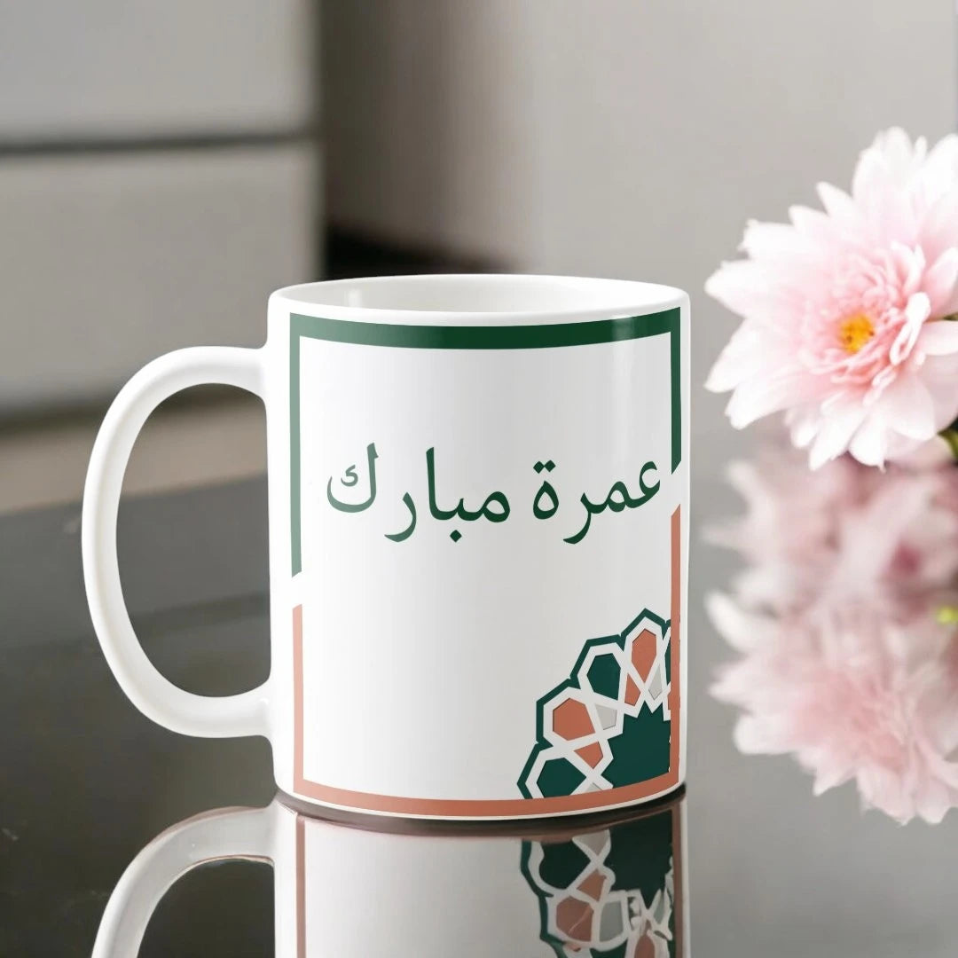 Umrah Mubarak Floral Mug with Arabic script and geometric floral design, 350 ml ceramic drinkware ideal for Umrah return gifts. Main image