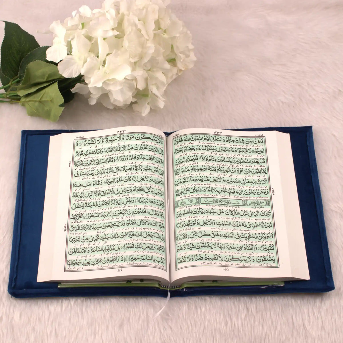 Open book with text on a blue cushion next to white flowers