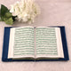 Open book with text on a blue cushion next to white flowers