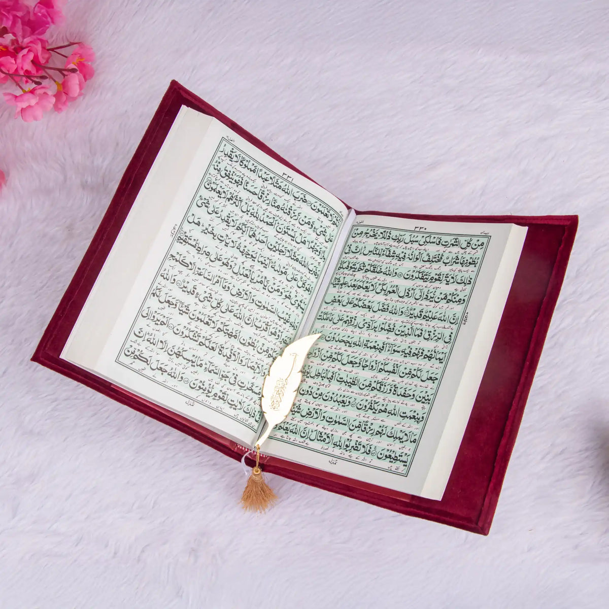 Open book with text, possibly a religious text, on a soft pink background with flowers.