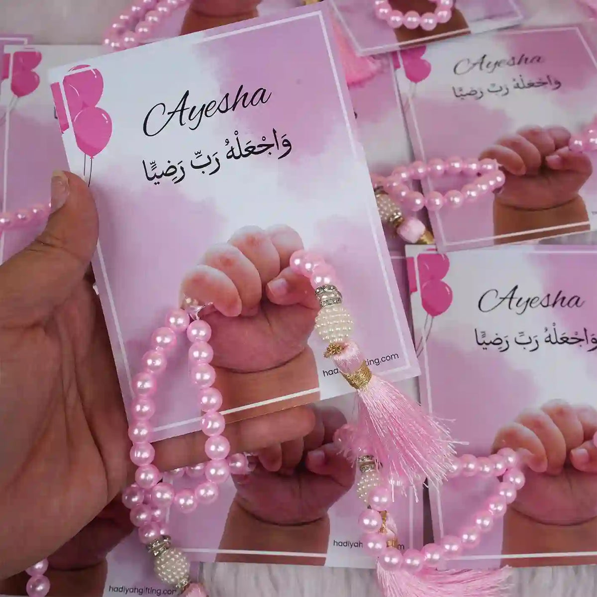 Close-up of pink Little Hands Tasbeeh Keepsake with name 'Ayesha' held in hand, a memorable Aqiqah wedding favor.