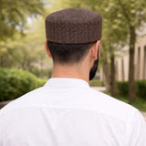Man wearing brown patterned prayer cap outdoors for Islamic prayer