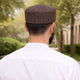 Man wearing brown patterned prayer cap outdoors for Islamic prayer