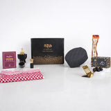 Front display of the Noble Ibadah Men's Hamper by Hadiyah, featuring a black gift box surrounded by a ghutra, Islamic book, bakhoor burner, prayer cap, miswak, and Ajwa dates.